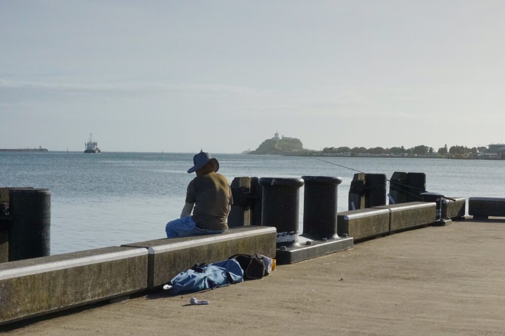 A lone fisherman sits along Queens Wharf, Newcastle.