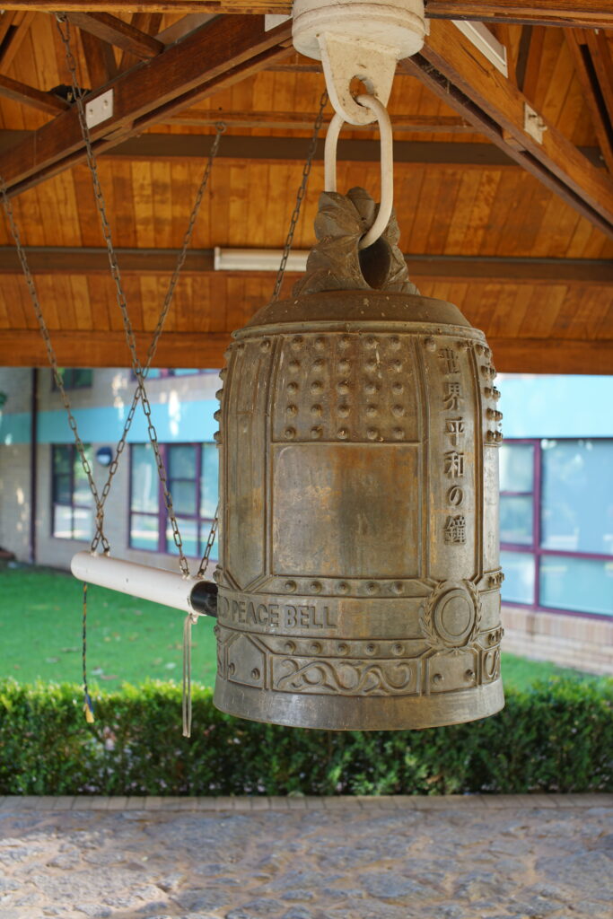 A large bronze bell hung under a pagoda, with the inscriptions: "World Peace Bell", "世界平和の鐘".