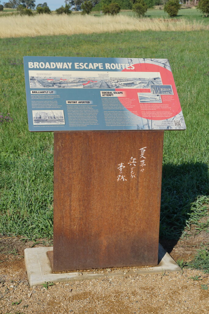 An informational board with the title "Broadway Escape Routes" detailing the paths escapees took at the Cowra Prisoners of War Camp. On the plinth underneath, an inscription reads: "夏草や　兵どもが　夢の跡".