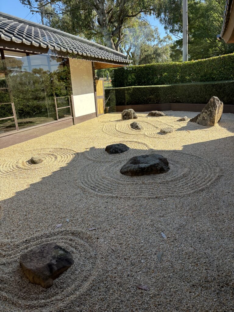 A dry garden with rocks and raked gravel.