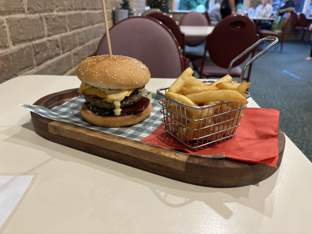 A burger and chips served on a wooden tray.